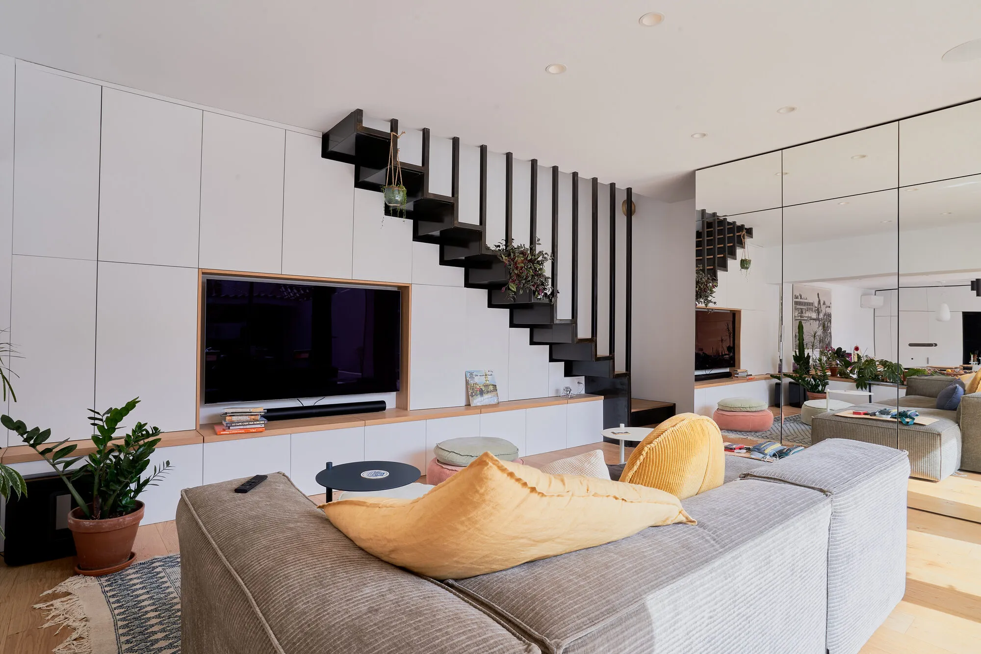 Salon avec escalier métallique suspendu et grand miroir