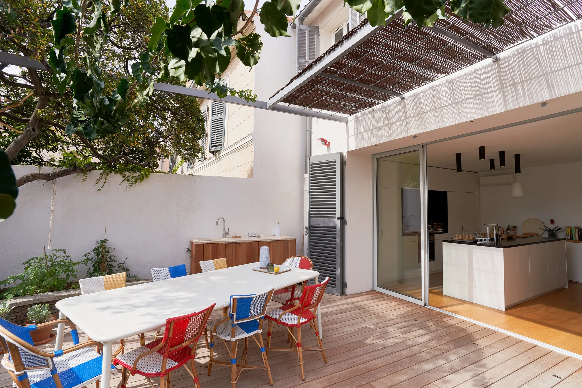 Terrasse avec table sous pergola et cuisine d’été