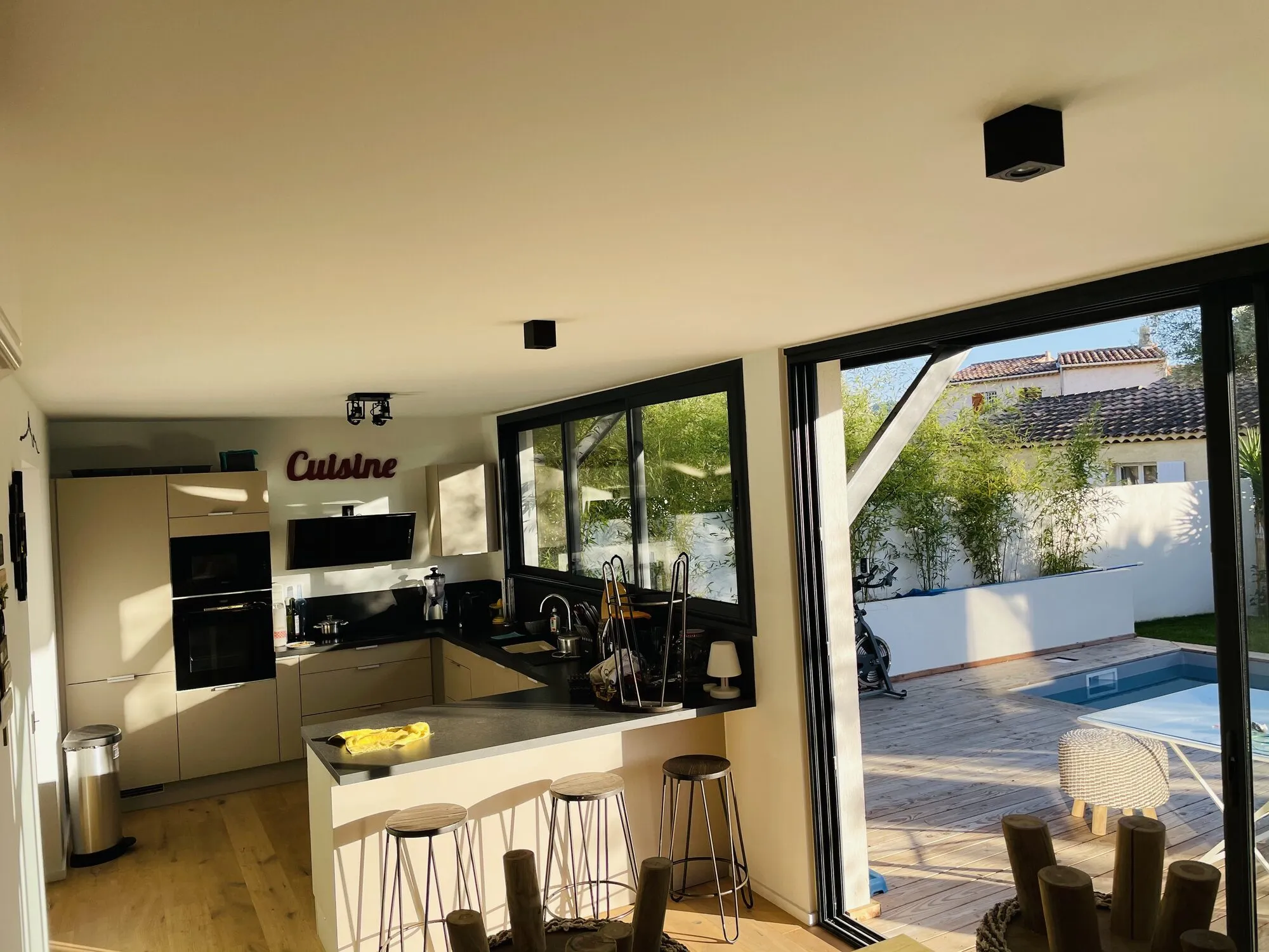 Cuisine ouverte avec îlot et baies vitrées sur la piscine