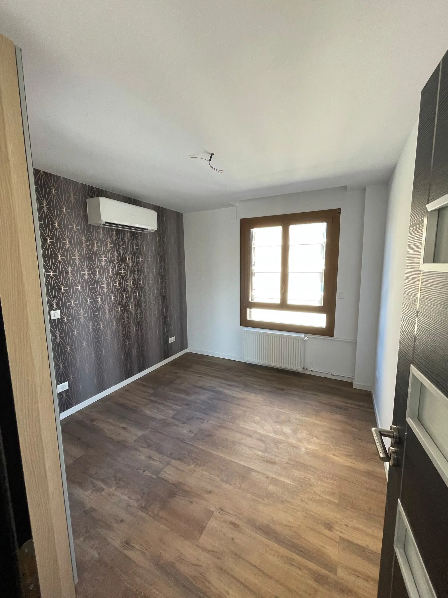 Chambre avec climatisation murale, papier peint et parquet