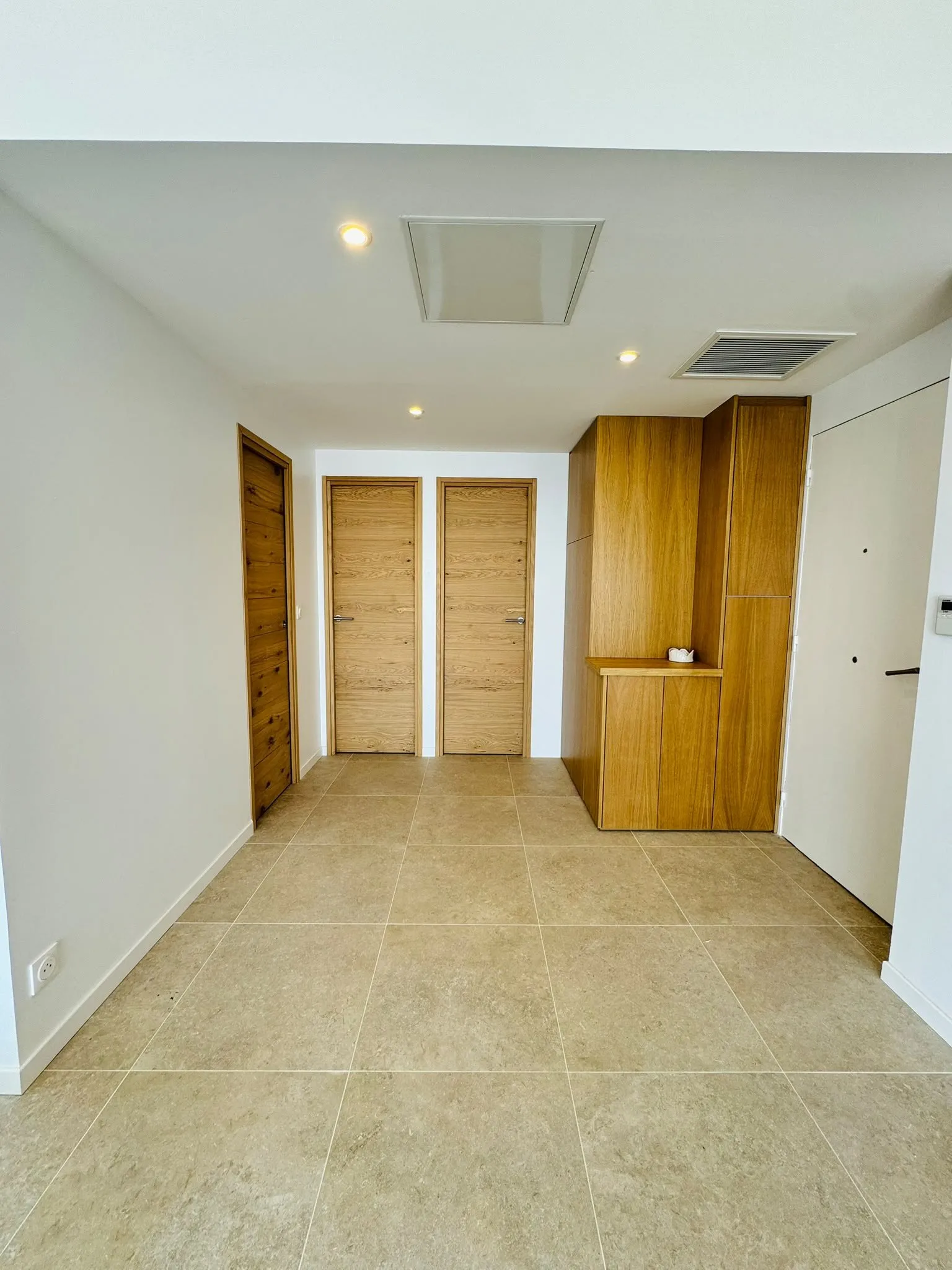 Entrée en carrelage grand format beige avec portes en chêne