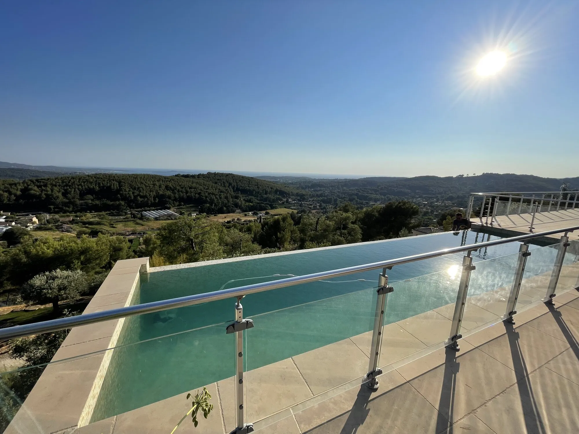 Piscine à débordement avec garde-corps en verre et vue sur les collines