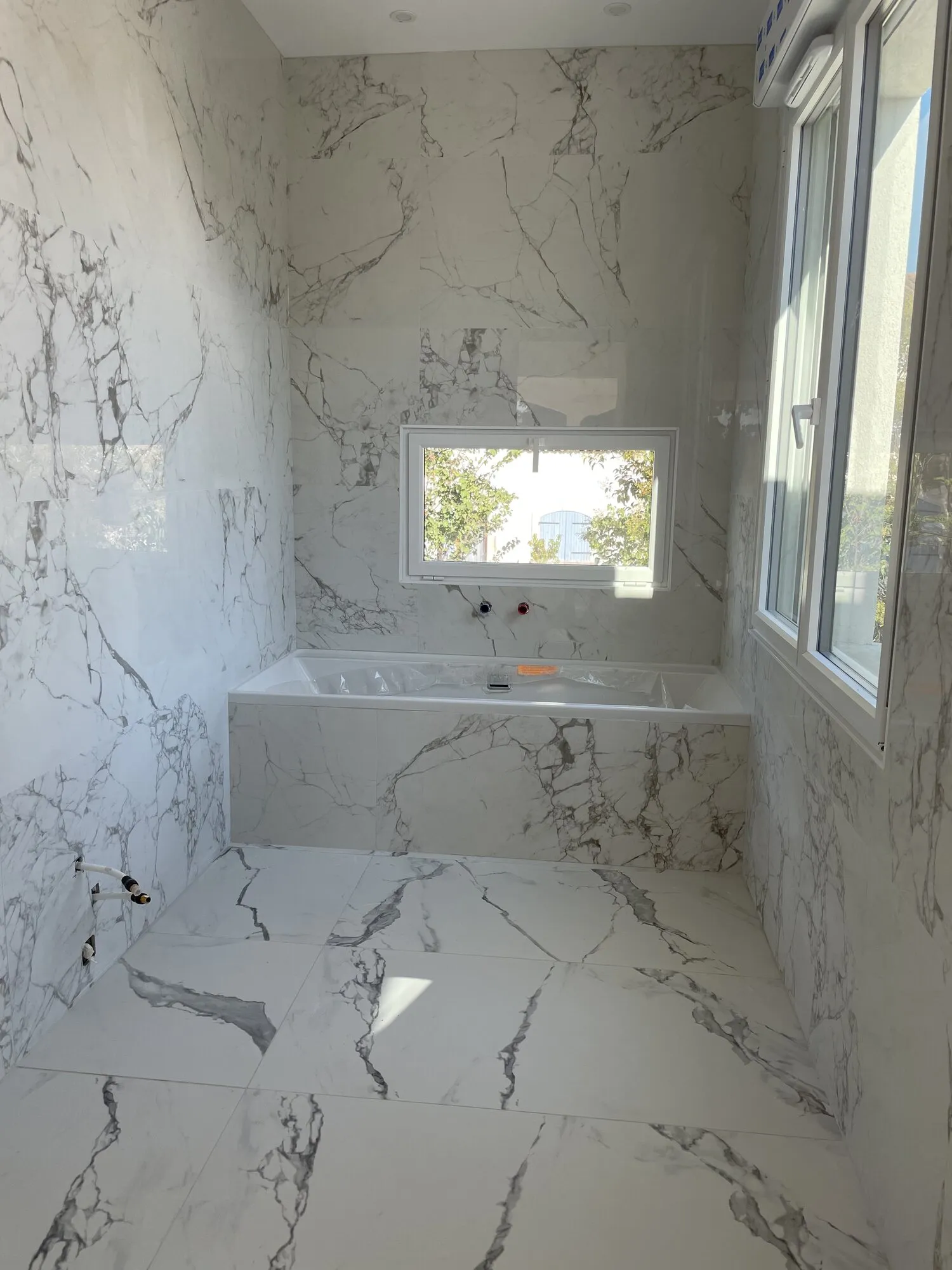 Salle de bains en carrelage effet marbre avec baignoire encastrée